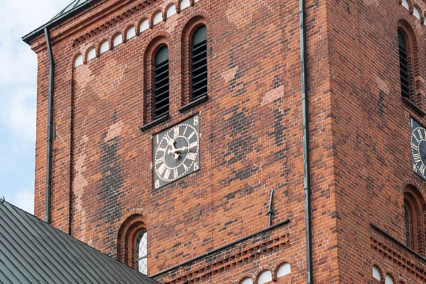 Turm der Marienkirche Bad Segeberg aus rotem Backstein mit zwei Uhren und spitzem Dach