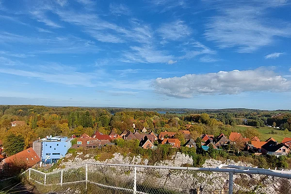 Blick über die Altstadt Bad Segebergs und einem blauen Haus vor einem bewaldeten Hügel unter blauem Himmel mit Wolken