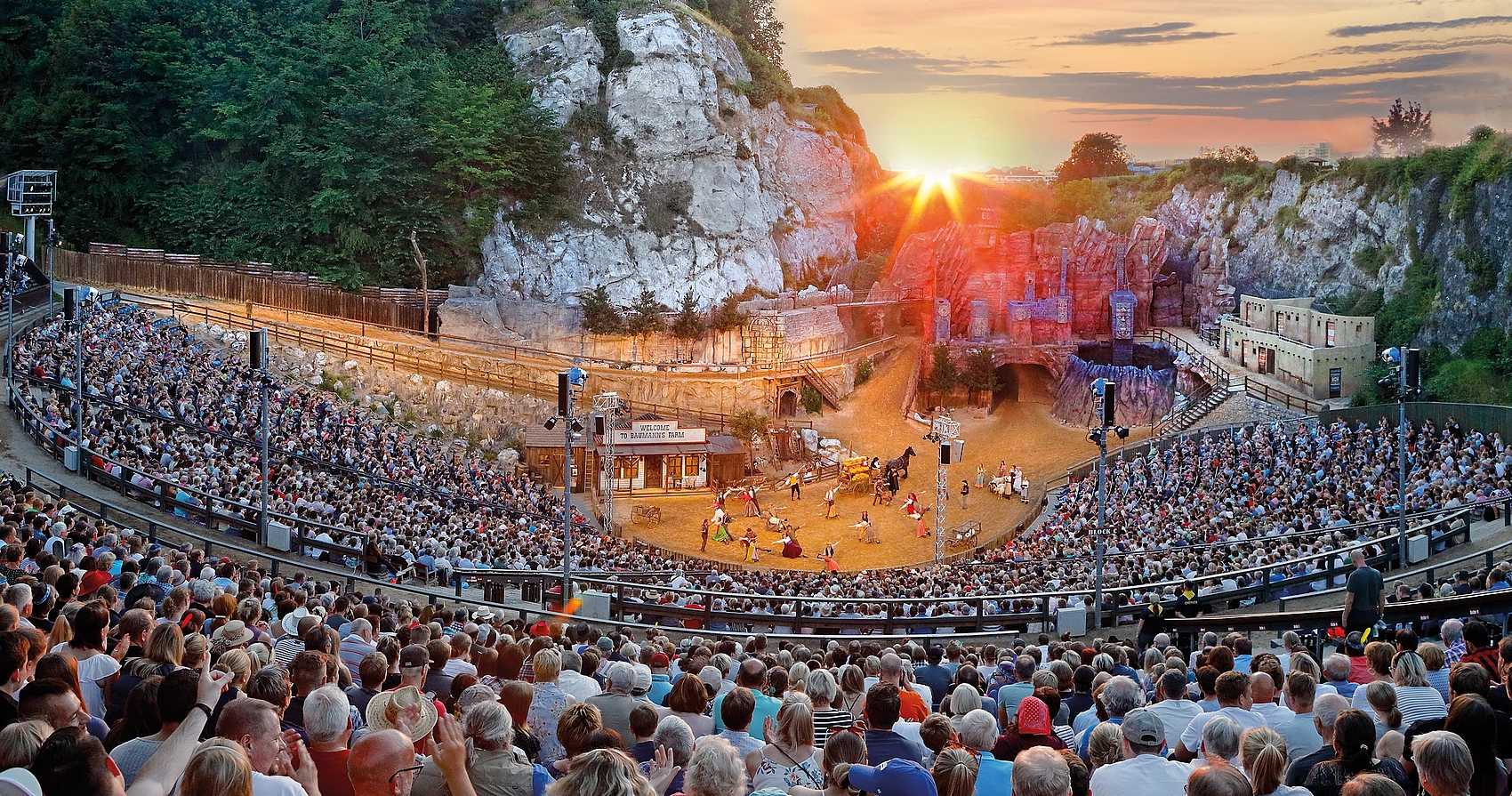 Großes Freilichttheater bei den Karl-May-Spielen Bad Segebergs mit vollbesetztem Zuschauerraum und Schauspielern auf der Bühne bei Sonnenuntergang