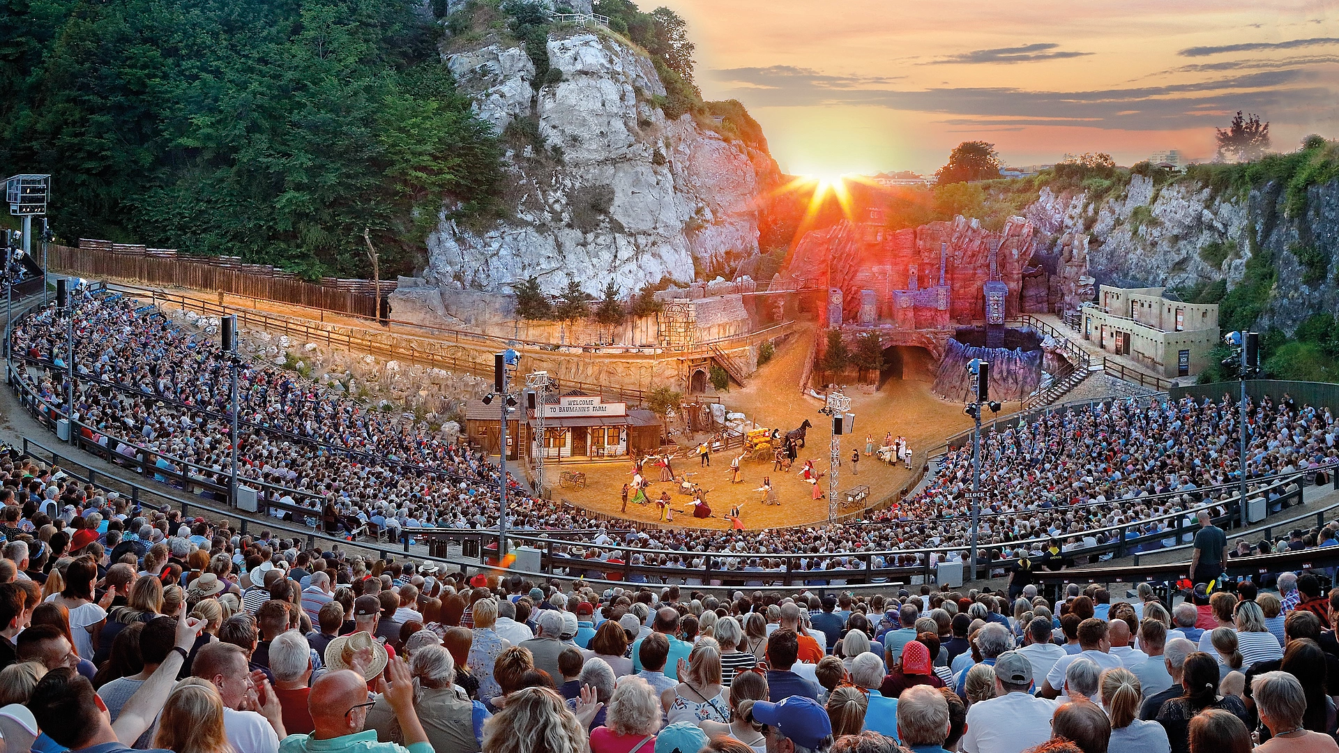 Großes Freilichttheater bei den Karl-May-Spielen Bad Segebergs mit vollbesetztem Zuschauerraum und Schauspielern auf der Bühne bei Sonnenuntergang