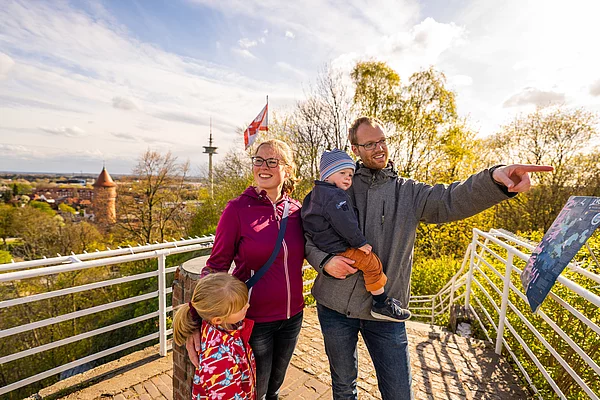 Familie mit zwei Kindern auf der Aussichtsplattform des Kalkbergs Bad Segeberg mit Blick auf einen Turm und einen Fernsehturm im Hintergrund