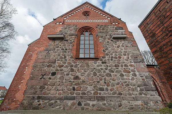 Fassade der Marienkirche Bad Segeberg mit Feldsteinmauerwerk und einem hohen, schmalen Fenster mit Backsteinrahmen