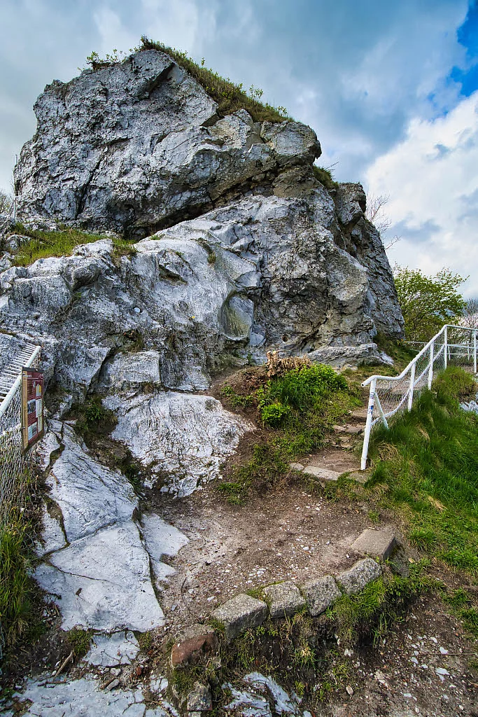 Felsformation am Kalkberg in Bad Segeberg mit Treppe und Geländer, umgeben von Gras und Sträuchern unter bewölktem Himmel