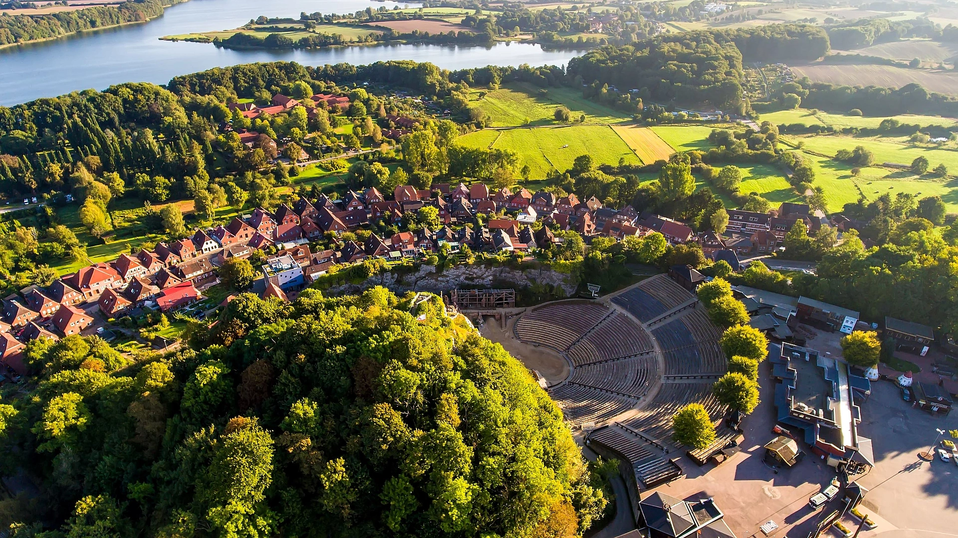Luftaufnahme von Bad Segeberg mit dem Kalkberg, dem Freilichttheater und dem umliegenden See sowie der Stadt