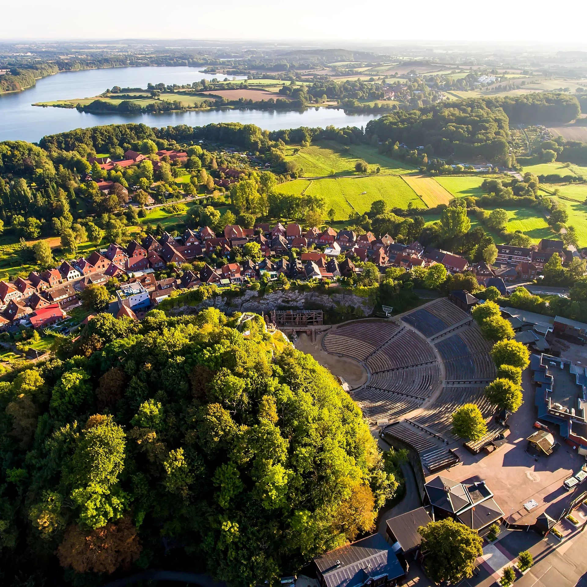 Luftaufnahme von Bad Segeberg mit dem Kalkberg, dem Freilichttheater und dem umliegenden See sowie der Stadt