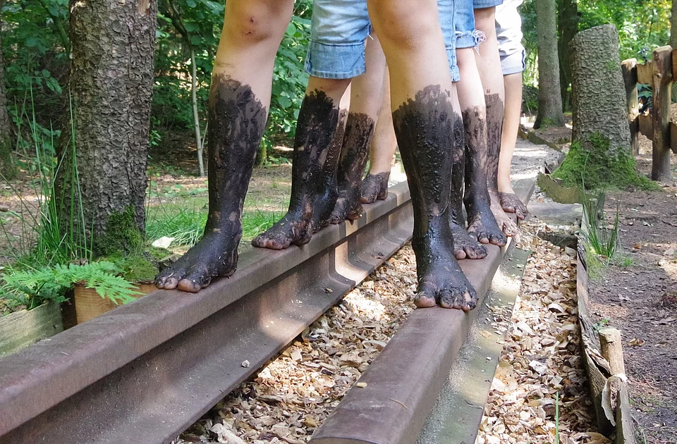 Eine Familie läuft im Barfußland mit matschigen Füßen auf dem Weg