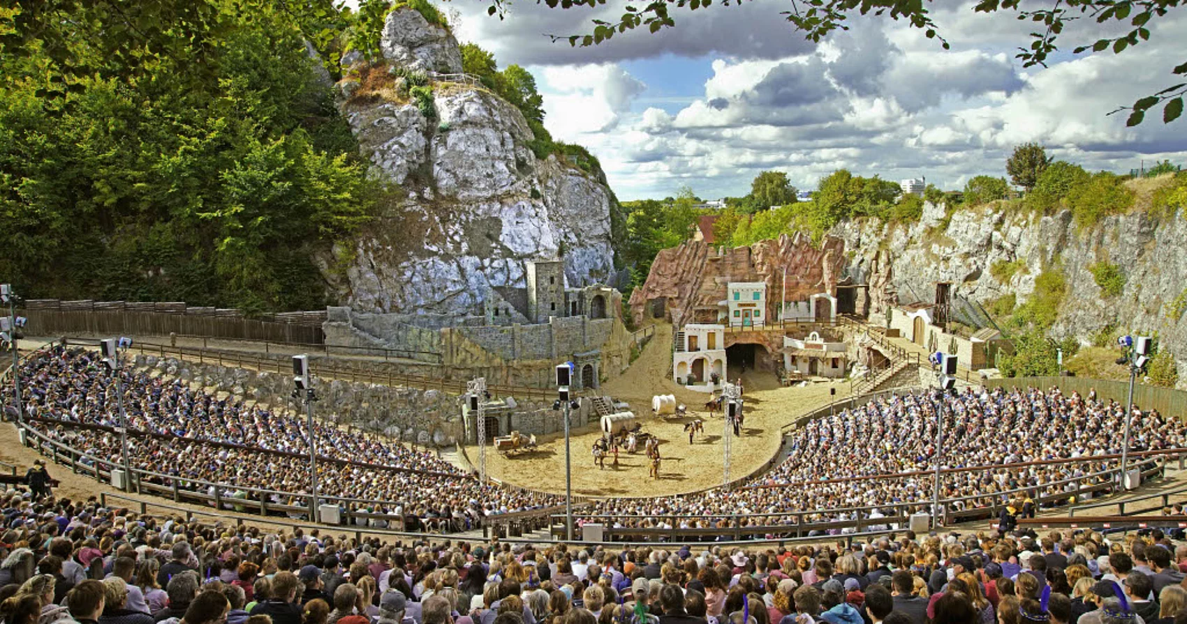 Freilichtbühne der Karl-May-Spiele Bad Segeberg mit Zuschauern und Westernkulisse vor Felsen unter bewölktem Himmel