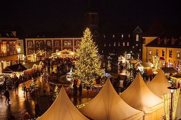 Weihnachtsmarkt in Bad Segeberg bei Nacht mit beleuchtetem großen Weihnachtsbaum, festlich geschmückten Ständen und Menschen auf dem Marktplatz