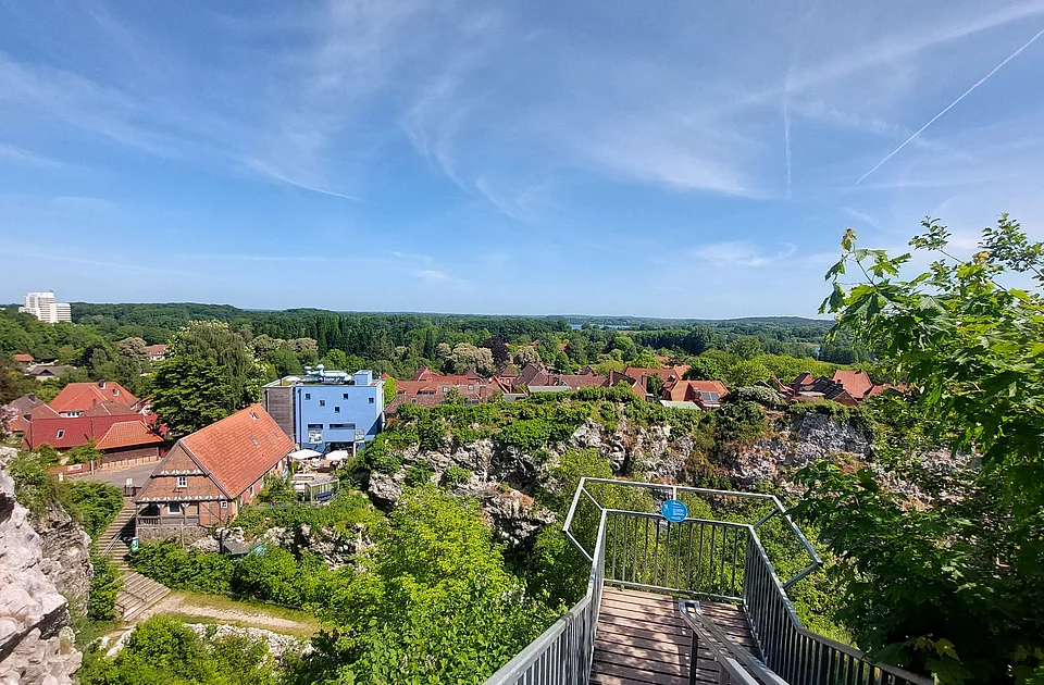 Blick vom Kalkberg in Bad Segeberg auf die Altstadt mit roten Dächern, einem blauen Gebäude und viel Grün unter blauem Himmel