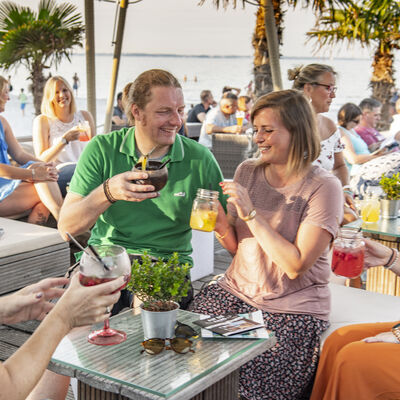 Bild vergrößern: Mehrere Personen sitzen in der Beachlounge in genießen verschiedene Getränke