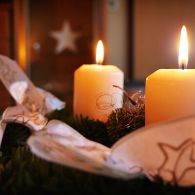 Bild vergrößern: Zwei Kerzen auf einem weihnachtlichen Gesteck