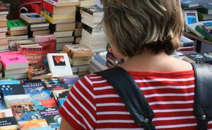 Eine Frau schaut sich am einem Flohmarkt-Stand Bücher an