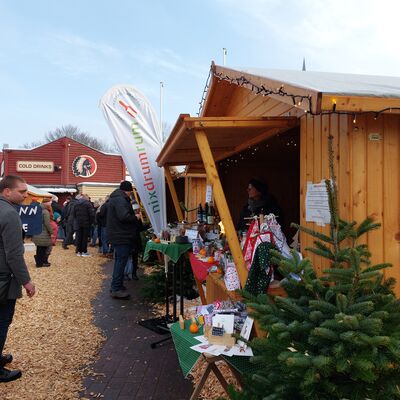 Bild vergrößern: Holzhütte, davor steht ein kleiner Tannenbaum. In der Auslage stehen viele kleine Dinge.