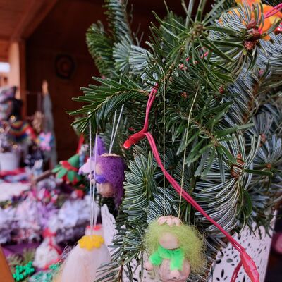 Bild vergrößern: Nahaufnahme von gebastelter Weihnachtsdeko, die an einem Tannenzweig hängt