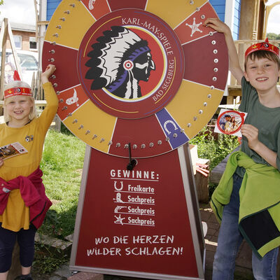 Bild vergrößern: Zwei Kinder stehen neben einem Glücksrad
