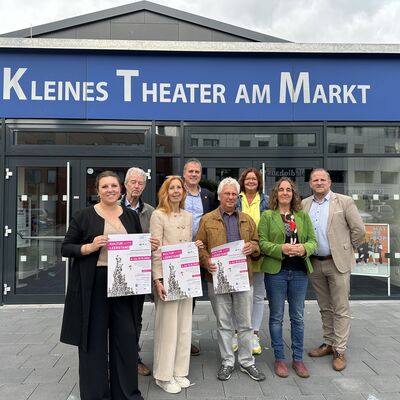 Eine Gruppe von acht Personen steht mit Plakaten in der Hand vor dem Theater in Wahlstedt