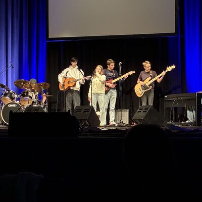 Bild vergrößern: and auf der Bühne des Kleinen Theaters in Wahlstedt mit Schlagzeug, zwei Gitarren, Bass, Keyboard und Sängerin vor blauem Bühnenvorhang.