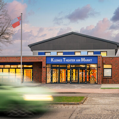 Bild vergr&ouml;&szlig;ern: Backsteinbau mit gro�em Eingangsbereich und blauem Schild mit der Aufschrift 'Kleines Theater am Markt'
